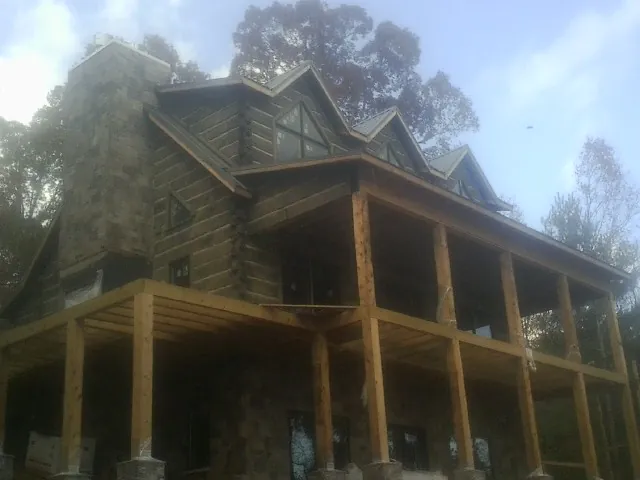 Stone chimney and dormers on a large log home with a timber porch in Scotland
